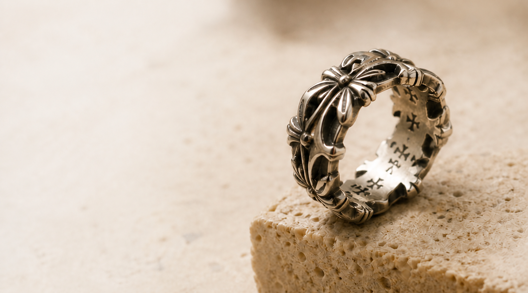 Ornate silver gothic ring on warm limestone