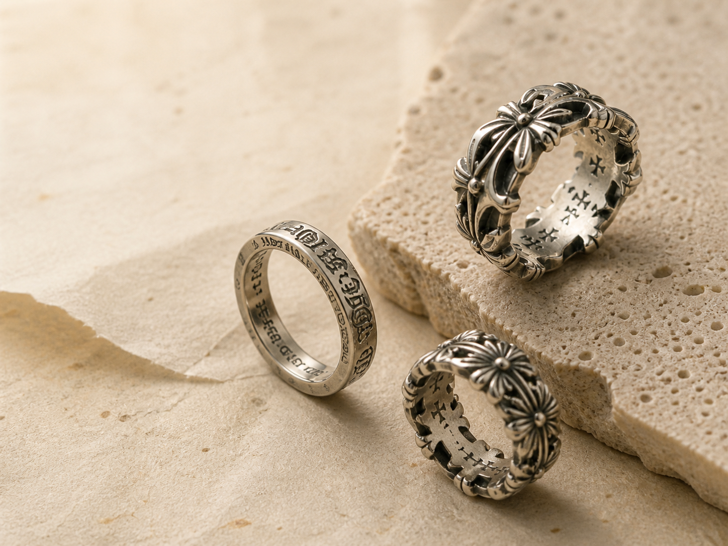 Three silver gothic rings on warm stone